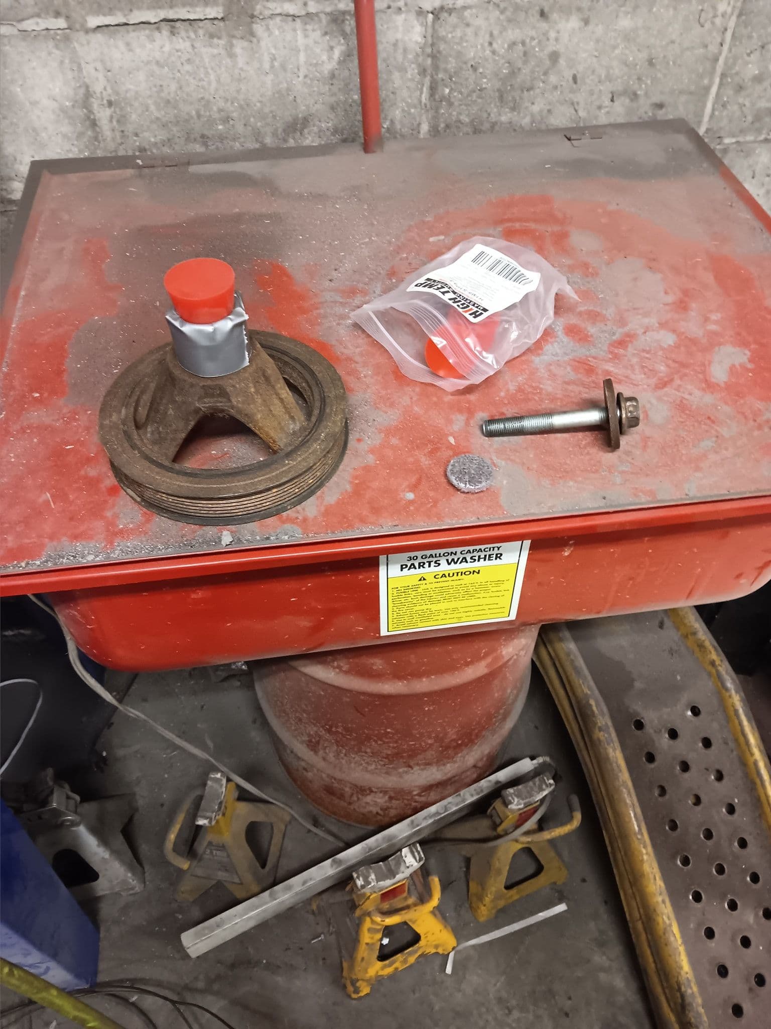 Parts washer setup with tools, washers, and a red metal workbench in a garage environment.